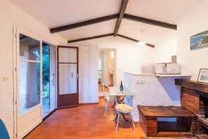 Ein gemütliches Zimmer mit Kamin, Essbereich und Blick durch eine Glastür.