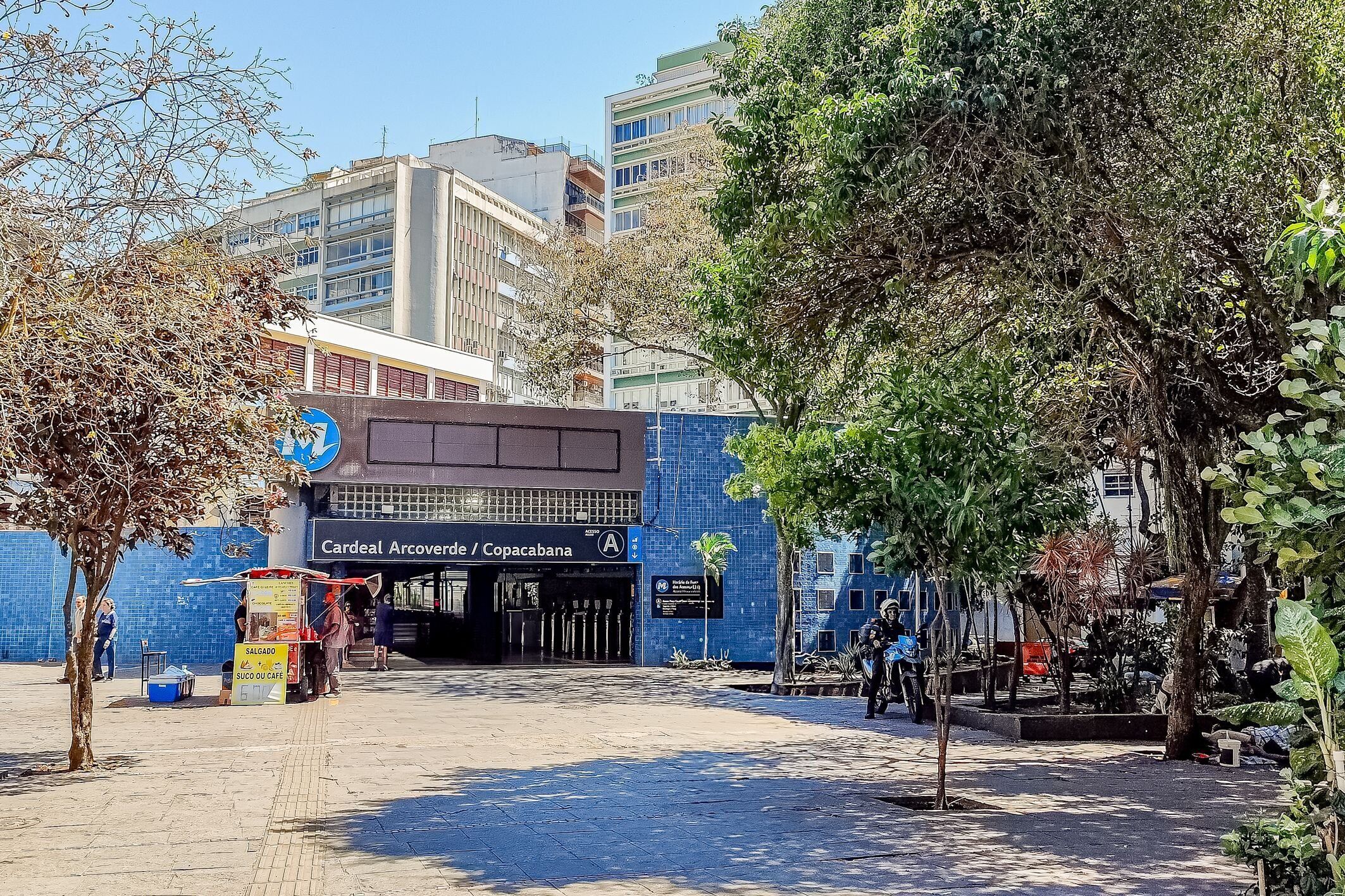A building entrance with a blue tiled wall, a sign for 'Cardenal Arcoverde / Copacabana', and a small kiosk.