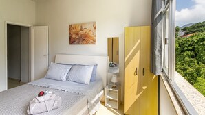 A bedroom with a bed, a bedside table with a lamp, a wardrobe, and a painting on the wall. - Copacabana - O coraçao do Rio (Rio de Janeiro)