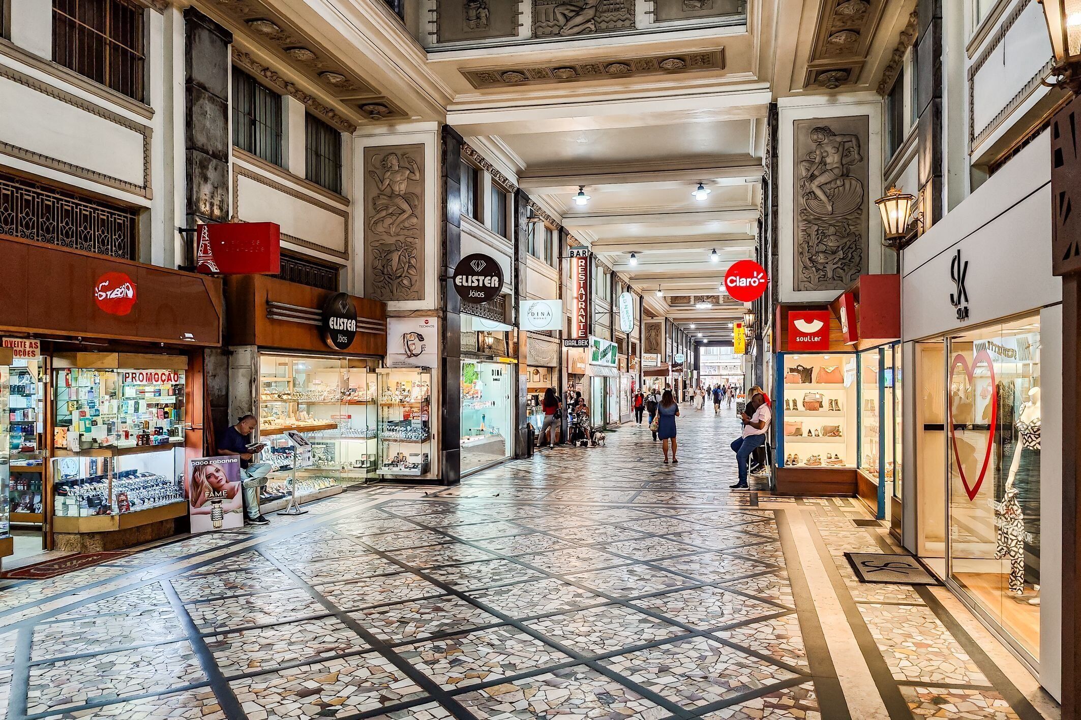 Un pasillo de centro comercial con diversas tiendas, incluyendo una joyería y un restaurante.