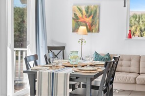 Un comedor con una mesa preparada para cuatro personas, una lámpara y un cuadro en la pared.