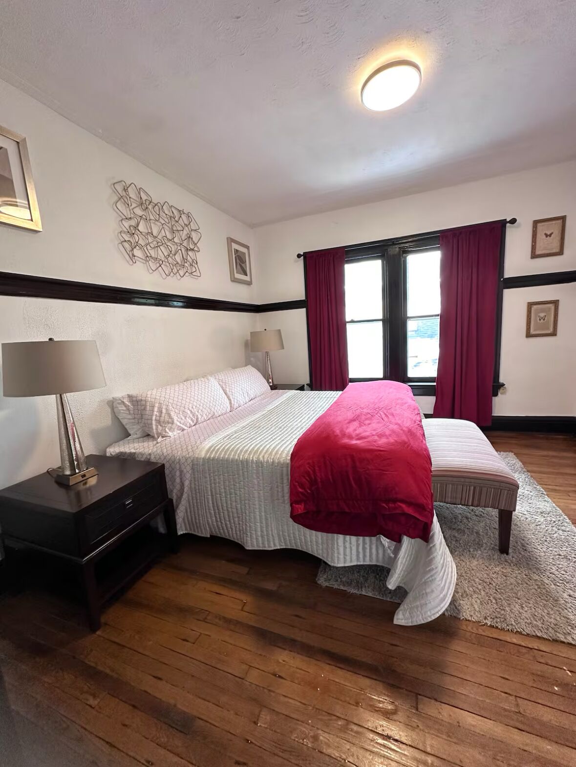 A bedroom with a bed, nightstand, lamp, and a window with curtains.