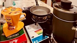 Une petite cuisine équipée d’une machine à café, d’une poêle et d’une tasse à café.