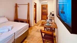 Une chambre à coucher avec un lit, deux lampes suspendues, un plafond en bois, un coin repas avec une table et des chaises, et une grande fenêtre donnant sur un beau paysage.