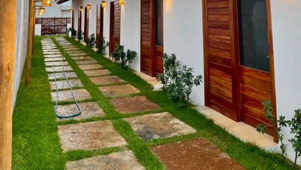 Un chemin menant à un bâtiment doté de portes en bois et d’un luminaire suspendu.