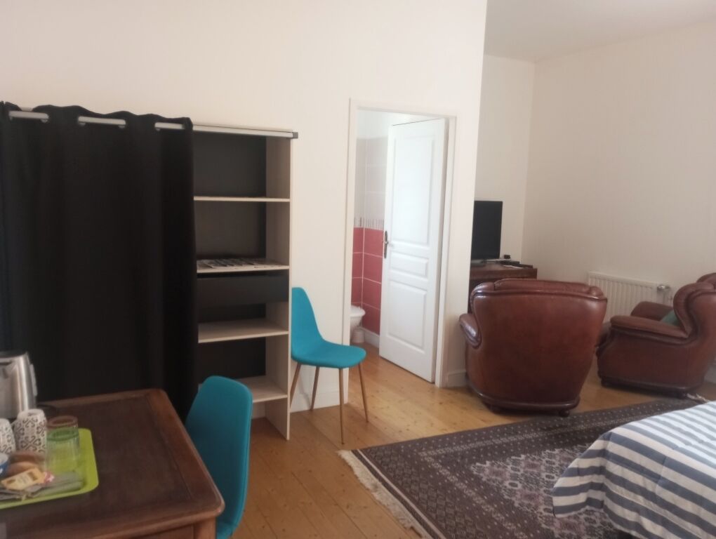 A living room with a sofa, a chair, a coffee table, a bookshelf, and a door leading to another room.