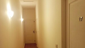 A narrow hallway with wooden flooring and white walls. A door with the number 17 is visible on the right.