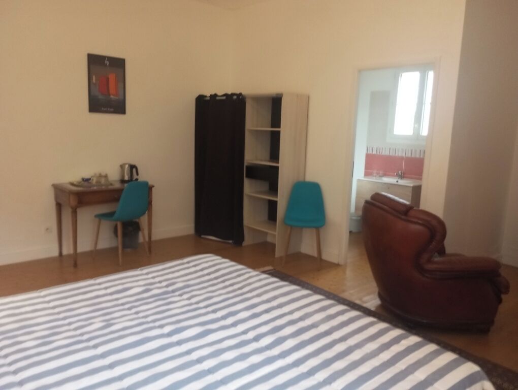 A bedroom with a bed, a desk, a chair, a wardrobe, and a bathroom.