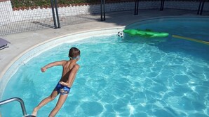 A swimming pool with clear blue water, a ladder, and a green inflatable float.