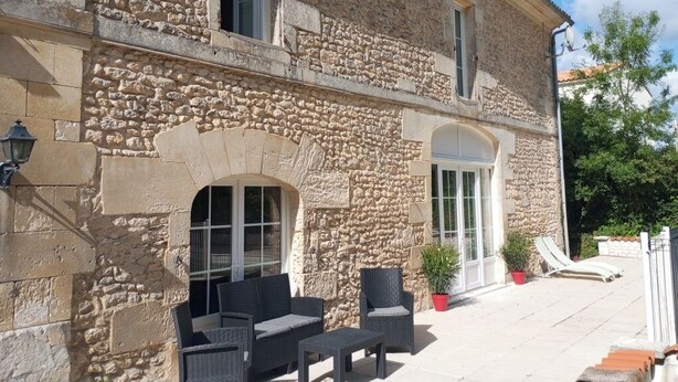 A stone building with a patio area featuring outdoor furniture and a potted plant.
