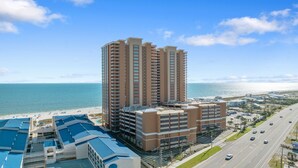 A high-rise hotel with multiple floors, a swimming pool, and a view of the ocean. - Beachfront 4BR, Lazy River/Slide, new complex! (Orange Beach)