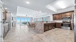 A spacious kitchen with modern appliances, a dining area, and a view to the outside. - Beachfront 4BR, Lazy River/Slide, new complex! (Orange Beach)