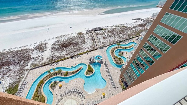 A resort with a large pool area featuring winding water features, a beach, and a view of the ocean. - Beachfront 4BR, Lazy River/Slide, new complex! (Orange Beach)