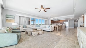 A spacious living room with a sectional sofa, a coffee table, and a dining area with chairs. - Beachfront 4BR, Lazy River/Slide, new complex! (Orange Beach)