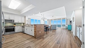 A spacious kitchen with white cabinetry, a wooden island, and a dining area with a view to the outside. - Penthouse 4BR, Beachfront!, Lazy River/Slide! (Orange Beach)