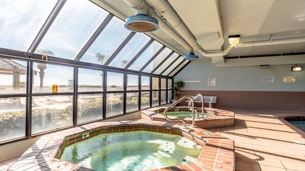 An indoor swimming pool with clear glass walls, a hot tub, and a bench. - Beachfront 2BR, Updated, Outdoor pool, Pickleball! (Orange Beach)