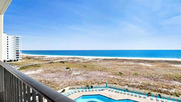 Un balcone d'hotel con vista sulla piscina e sulla spiaggia.