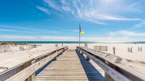 Una passerella in legno che conduce a una spiaggia, con un'antenna e una bandiera.