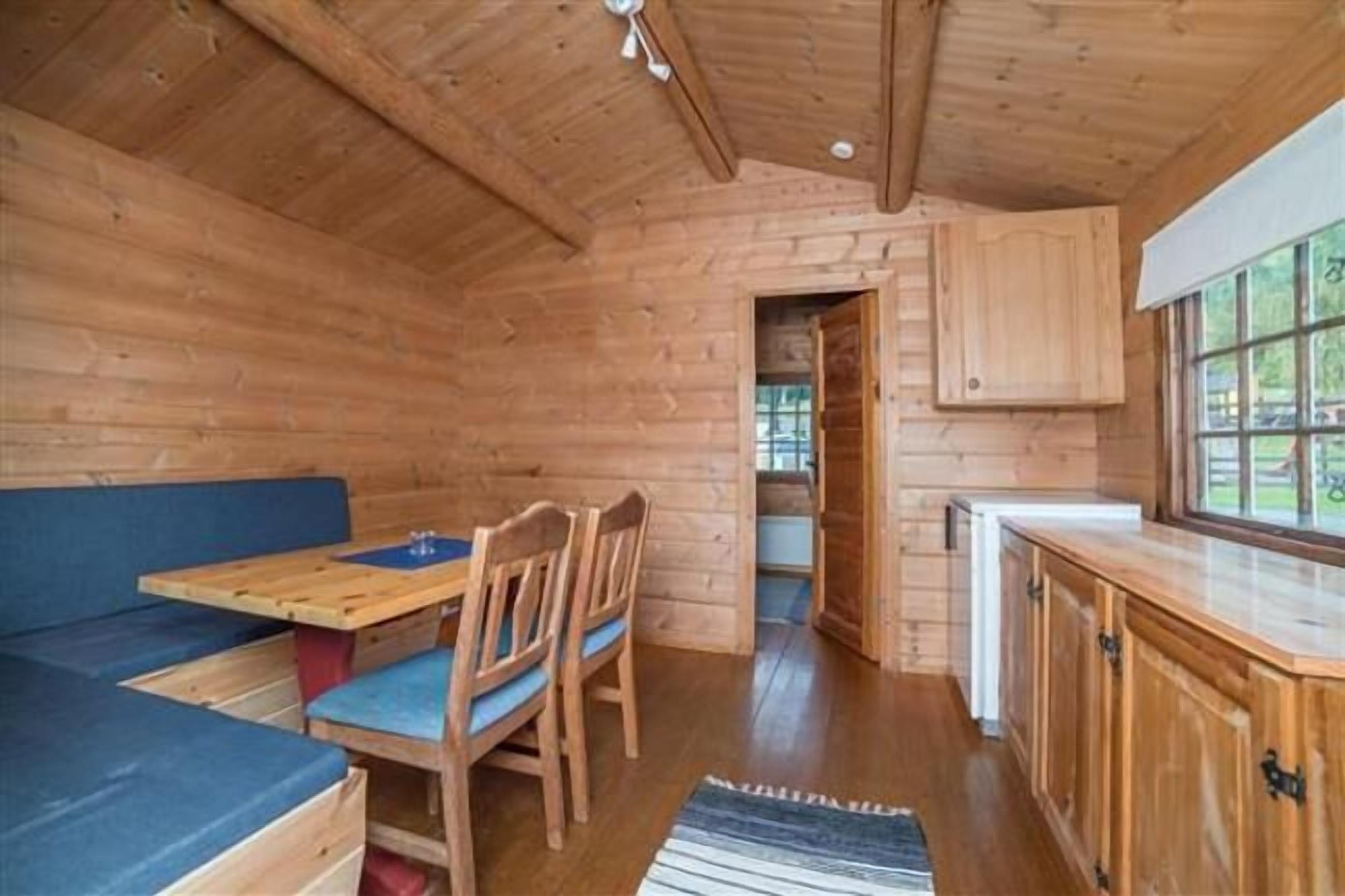 A wooden cabin interior with a dining area, a bench, and a kitchen counter.