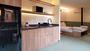 A modern kitchen with a built-in refrigerator, microwave, and sink. There is a small seating area with a bed and a bedside table. - w Beautiful 1BR w Terrace in Poblado (Medellín)