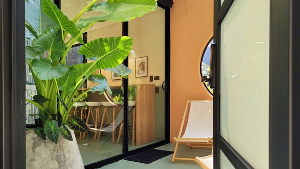 A modern interior with a large potted plant, a wooden table with chairs, and a white easel. - w Beautiful 1BR w Terrace in Poblado (Medellín)