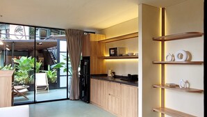 A modern kitchen with wooden cabinets, a black refrigerator, and a dining area with a table and chairs. - w Beautiful 1BR w Terrace in Poblado (Medellín)