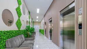 A modern lobby with a marble floor, a sofa, a green wall with plants, and an elevator. - w Dreamy 1BR w Stunning Cinta Costera Views (Panama City)