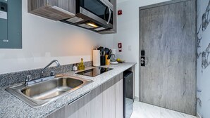 A modern kitchen with a stainless steel sink, a microwave, and wooden cabinets. - w Dreamy 1BR w Stunning Cinta Costera Views (Panama City)