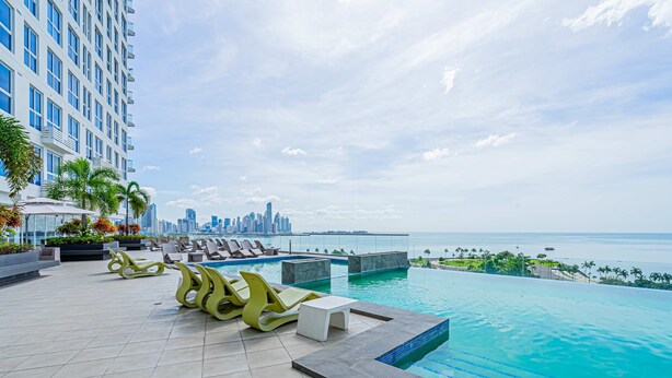 A rooftop pool area with lounge chairs and a view of the city skyline. - w Dreamy 1BR w Stunning Cinta Costera Views (Panama City)