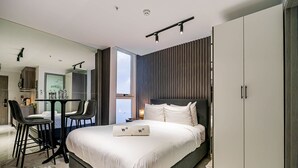 A modern hotel room with a large bed, a desk with two chairs, a wardrobe, and a view of the city. - w Dreamy 1BR w Stunning Cinta Costera Views (Panama City)