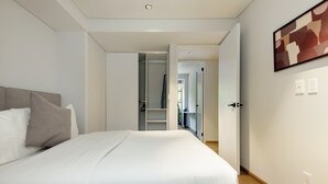 A modern hotel room with a large bed, a wardrobe, and a hallway leading to other rooms. - w Awesome 2BR in Roma Norte (Mexico City)