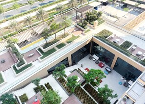 A modern building with a rooftop terrace featuring outdoor seating and greenery. - Stayshort - Cozy 1BR Apartment Located in Dubai Hills (Dubai)