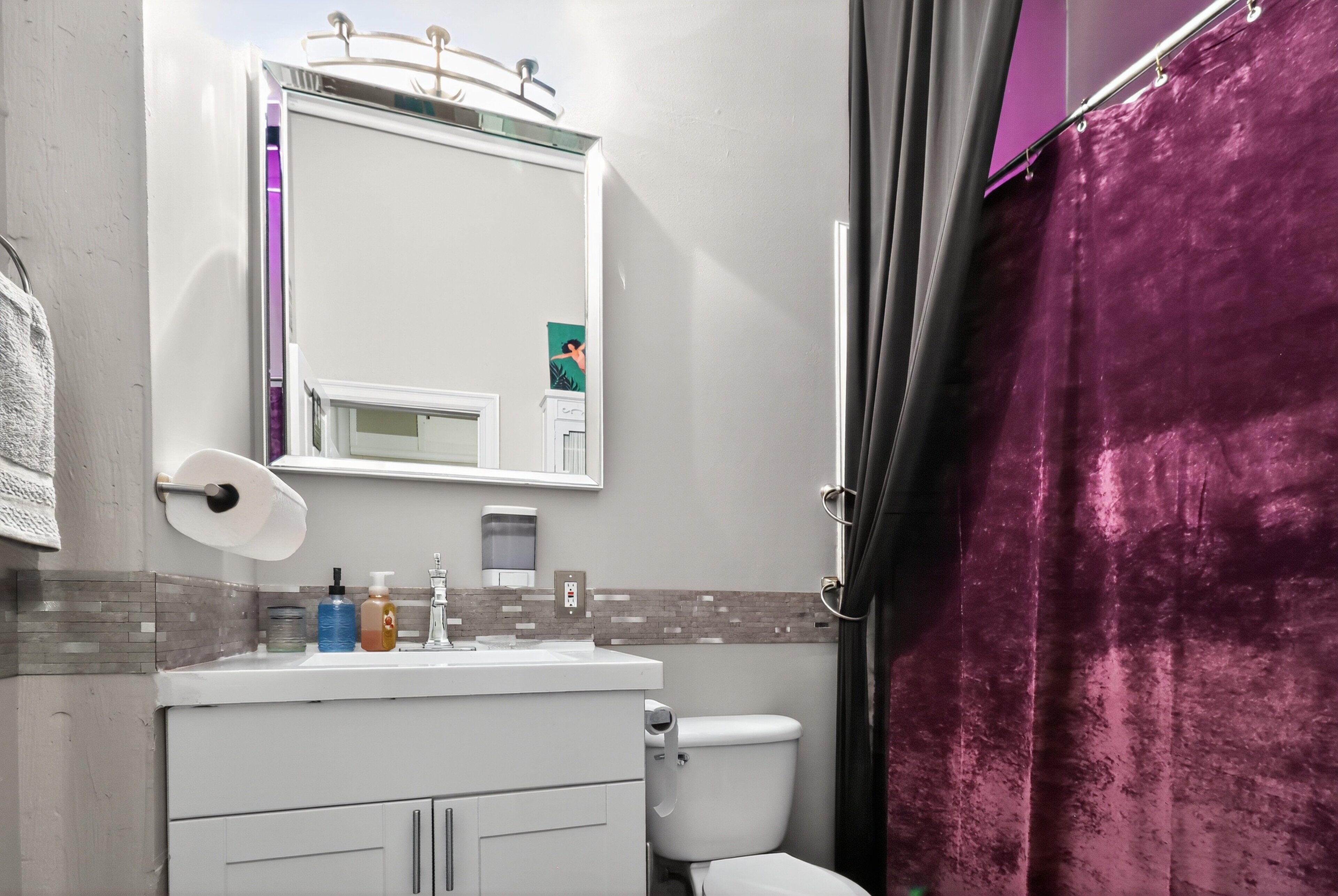 Un baño con lavamanos, espejo e inodoro blancos.