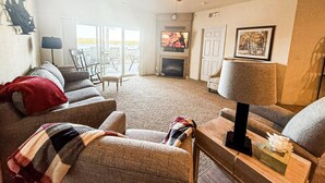 Ein Wohnzimmer mit Kamin, Deckenventilator und Fernseher.
