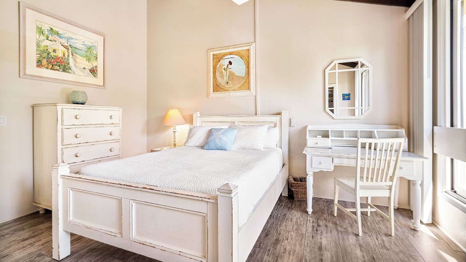 Een slaapkamer met een bed, een bureau, een stoel, een kast en een spiegel.