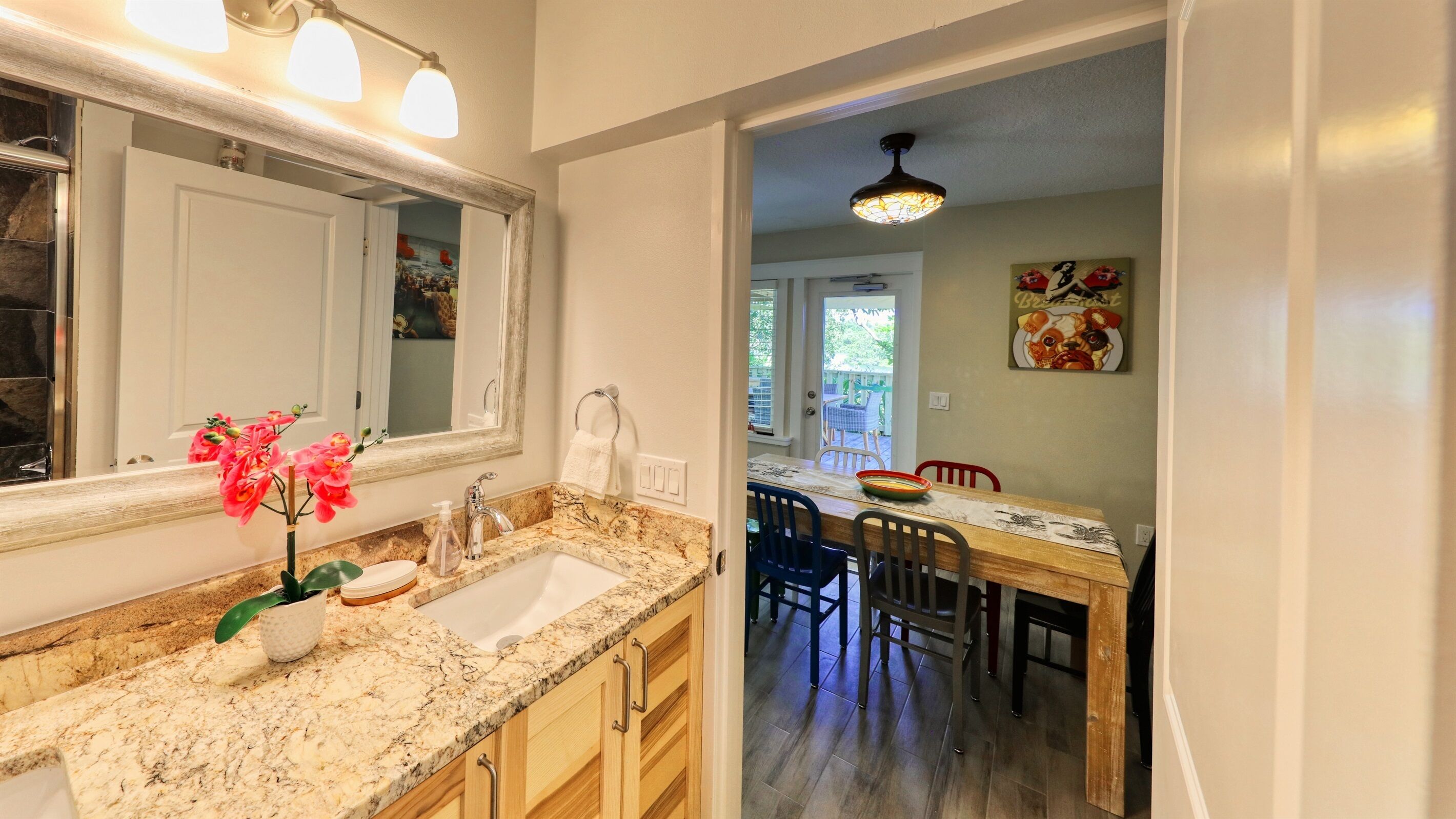 A kitchen with granite countertops, a sink, and a dining area with a wooden table and chairs.