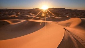 A desert landscape with sand dunes and the sun setting in the background. - Lantern Luxury Camp (Merzouga)
