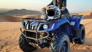 A person on a blue off-road vehicle in a desert with sand dunes in the background. - Lantern Luxury Camp (Merzouga)