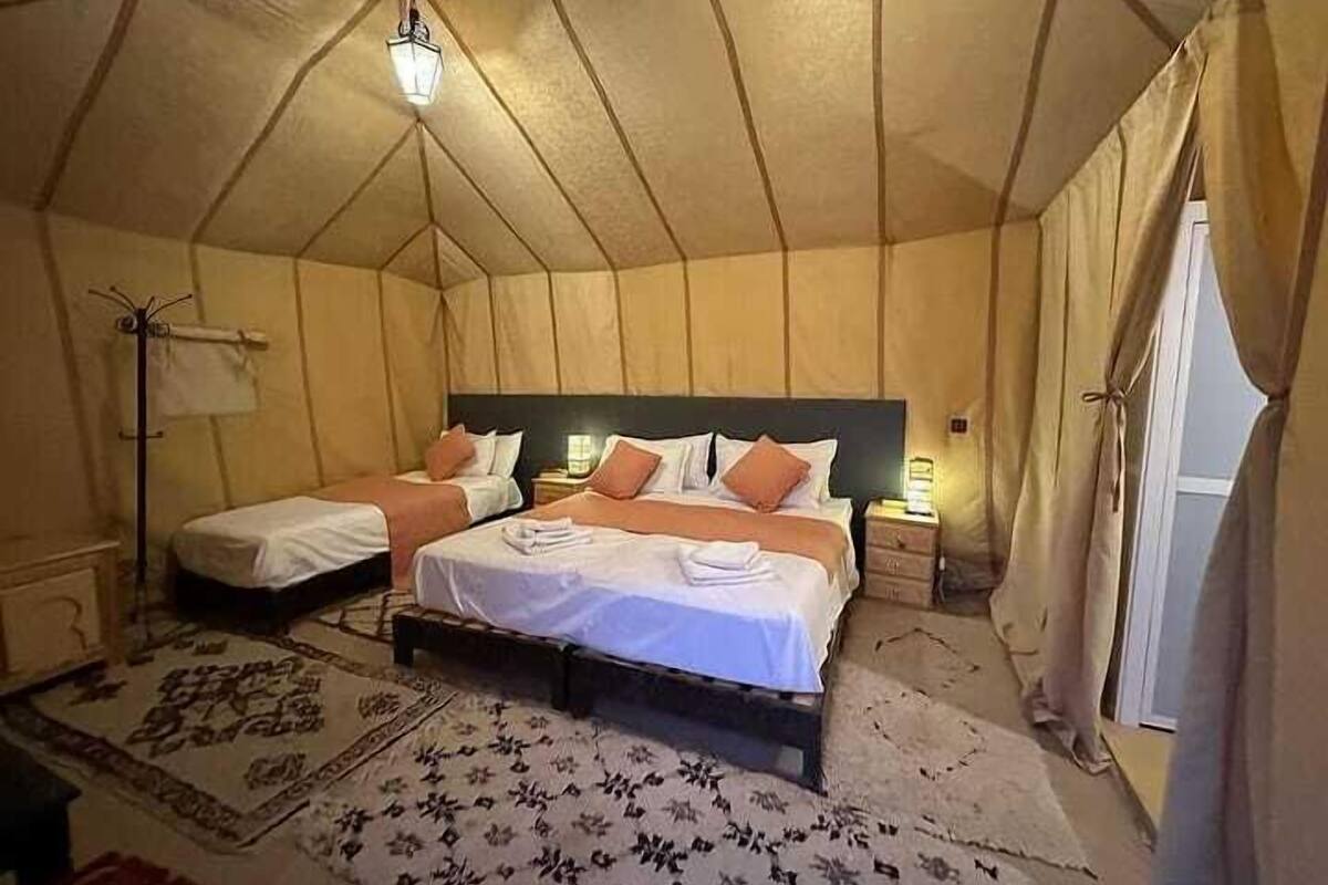 A tent-style room with two beds, a floor lamp, and a patterned rug.