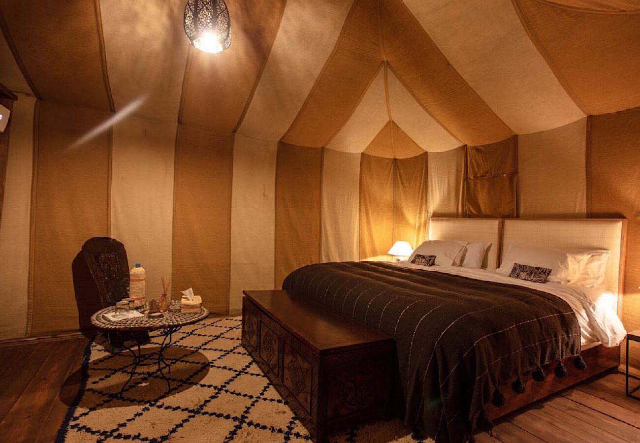 A tent-style room with a bed, a small table with candles, and a chair.