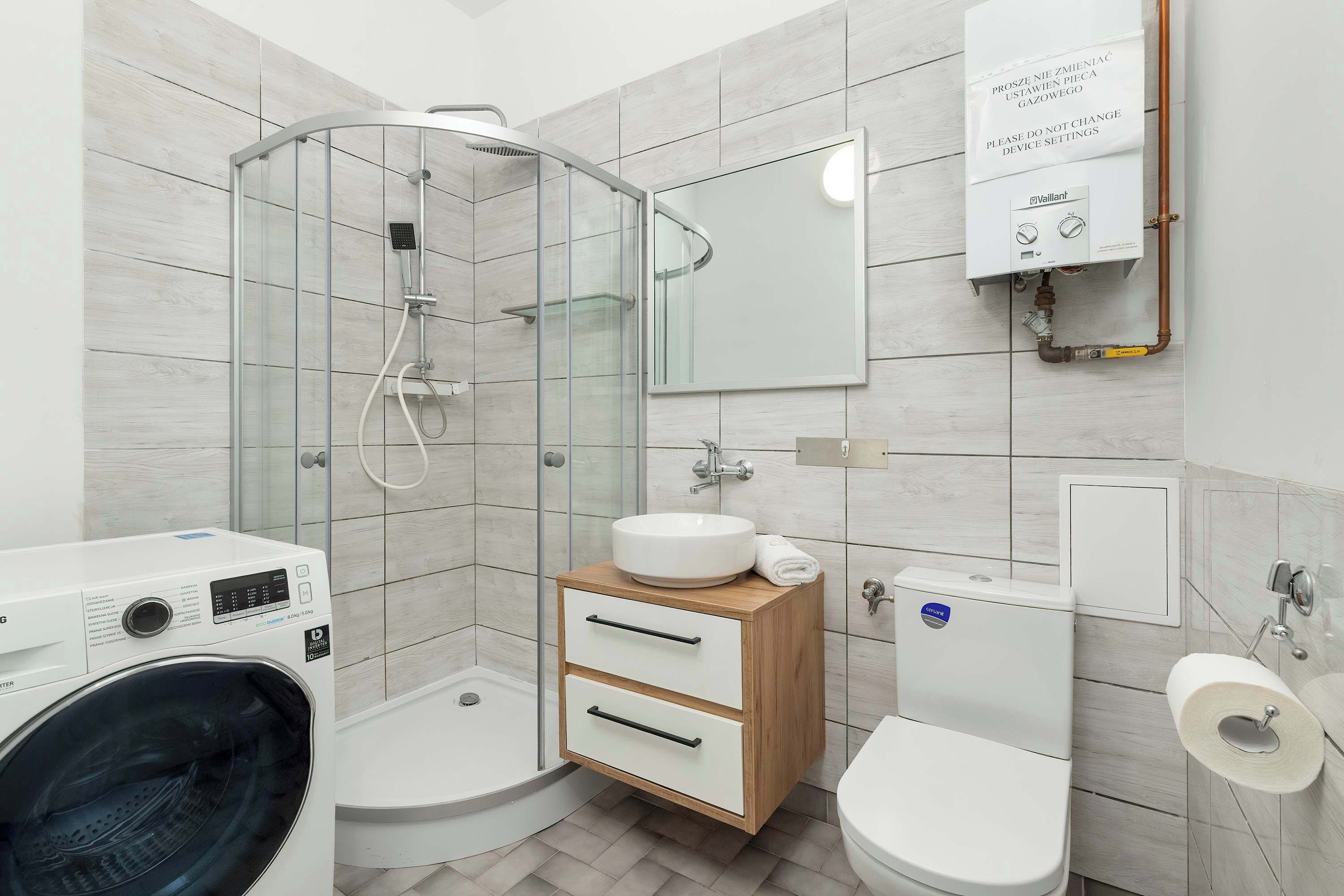 Un bagno moderno con box doccia in vetro, lavabo a incasso, water e lavatrice.
