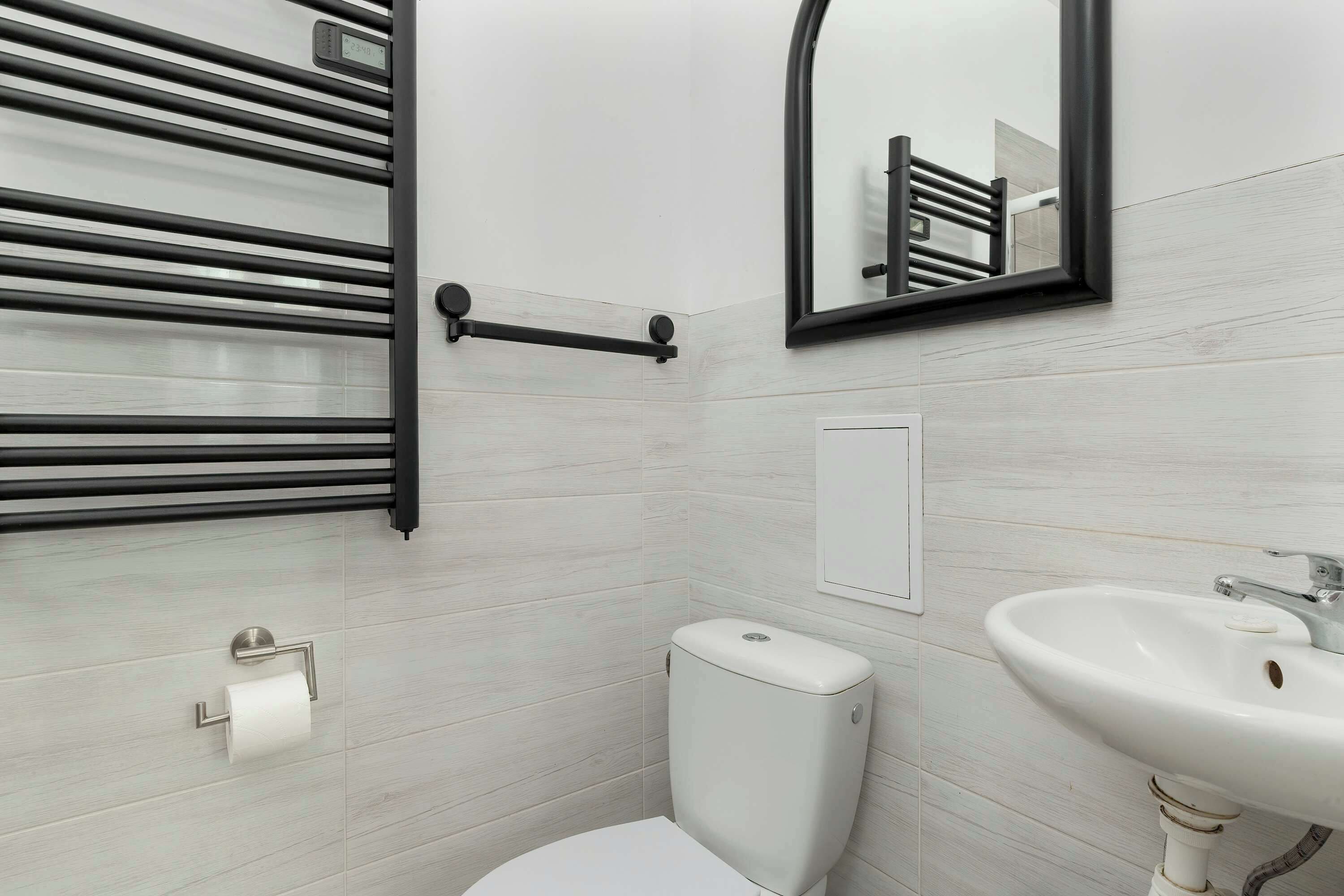 A modern bathroom with a toilet, sink, and towel rack.