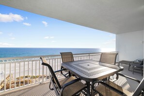 Ein Balkon mit Tisch und Stühlen mit Blick auf Strand und Meer.