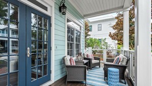 Eine überdachte Veranda mit Korbmöbeln und einem blauen Teppich.