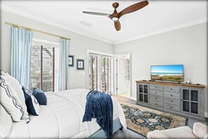Un dormitorio con cama, ventilador de techo, televisión y armario.
