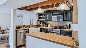 Une cuisine avec des poutres en bois, des appareils en acier inoxydable et des luminaires suspendus.