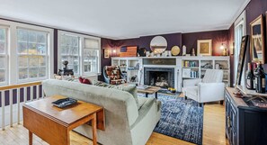 Ein Wohnzimmer mit Kamin, einer Couch, einem Couchtisch und einem Bücherregal.