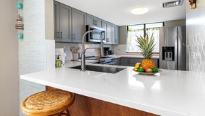 Una cocina moderna con armarios grises, electrodomésticos de acero inoxidable y una encimera de mármol blanco.