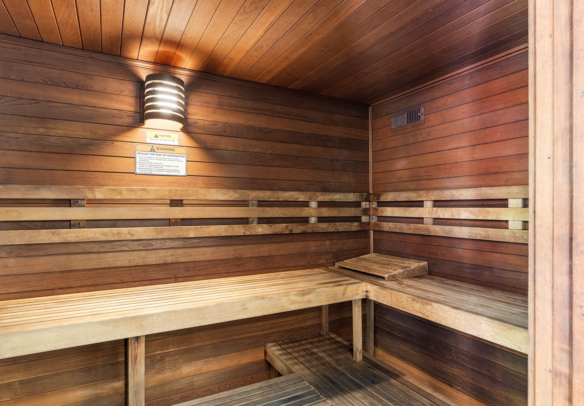 A wooden sauna with benches and a wall-mounted heater.
