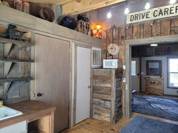 Une cuisine rustique avec des murs en bois, un four à micro-ondes et un panneau indiquant « Service au volant ».